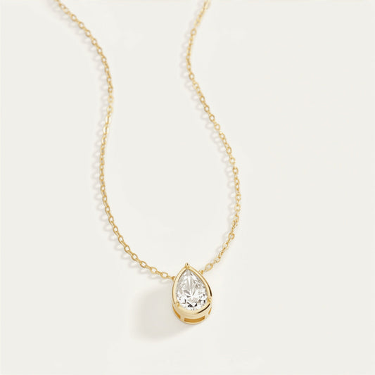Gold necklace with a teardrop-shaped diamond pendant on a white background