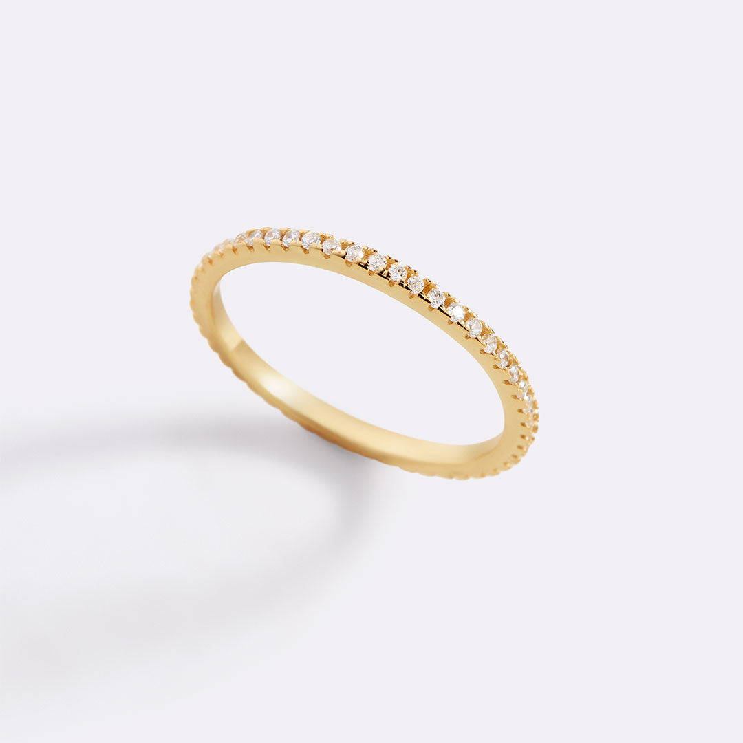 Gold ring with small diamonds on a light gray background