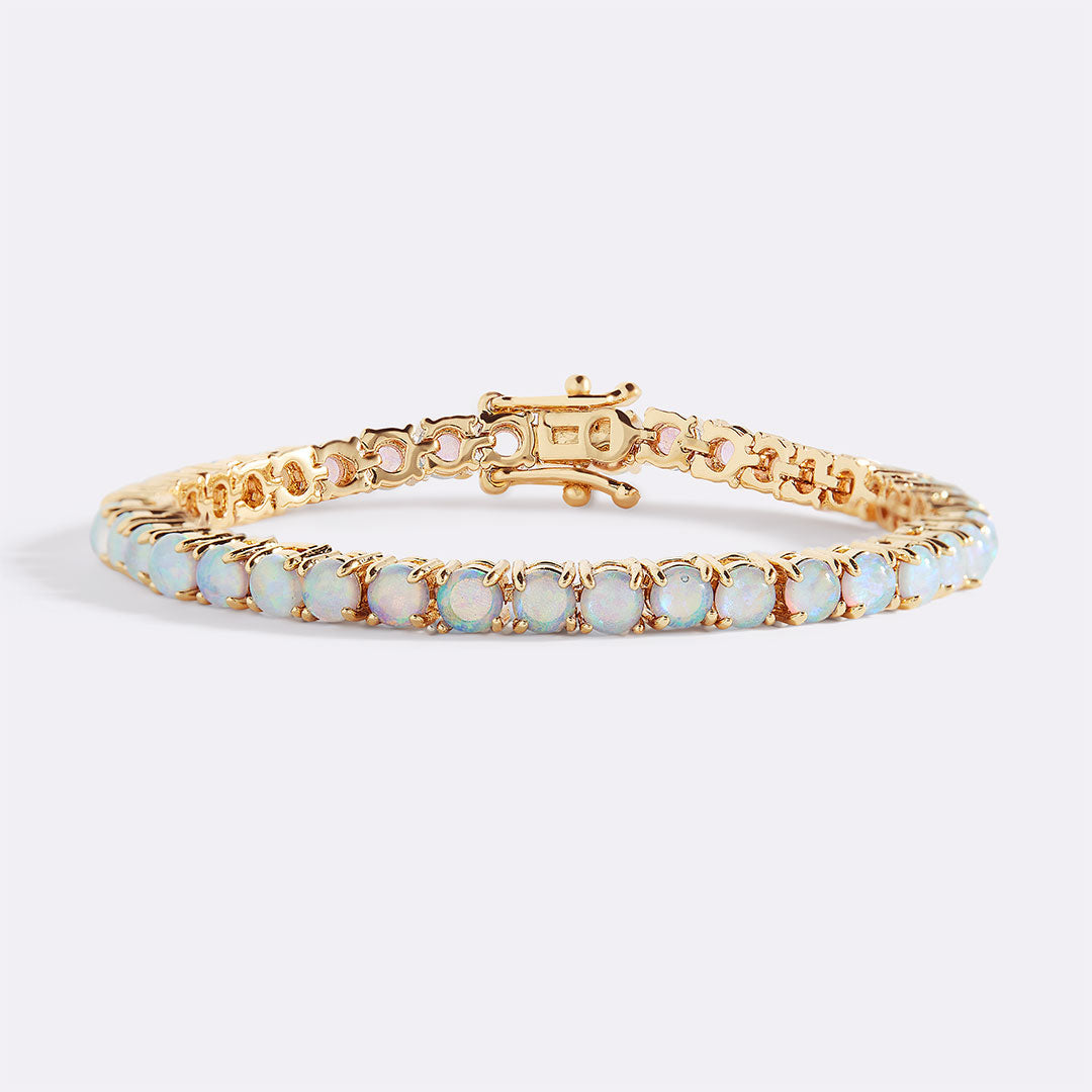 Gold bracelet with opal stones on a light gray background