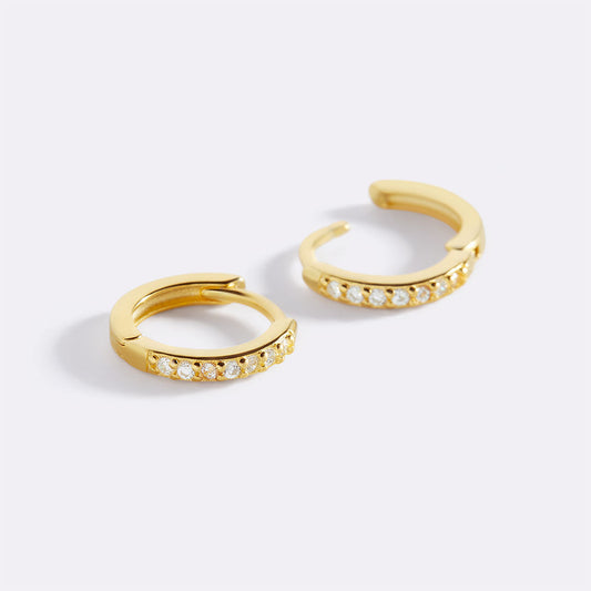 Gold hoop earrings with small diamonds on a white background