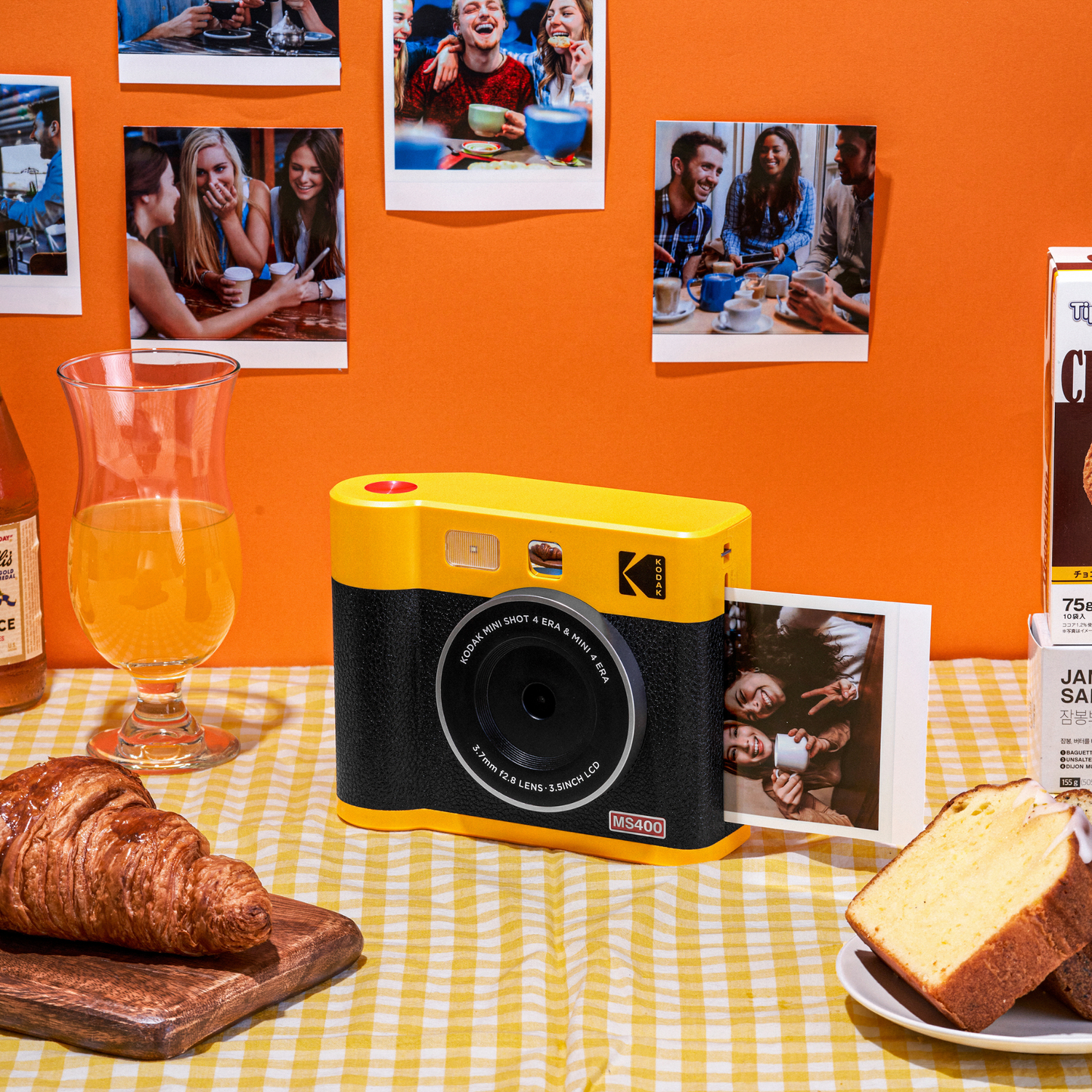 Yellow and black camera on a table with food and photos in the background