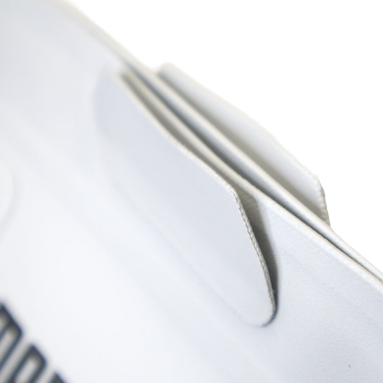 Close-up of a white sneaker with a brand logo on a light gray background