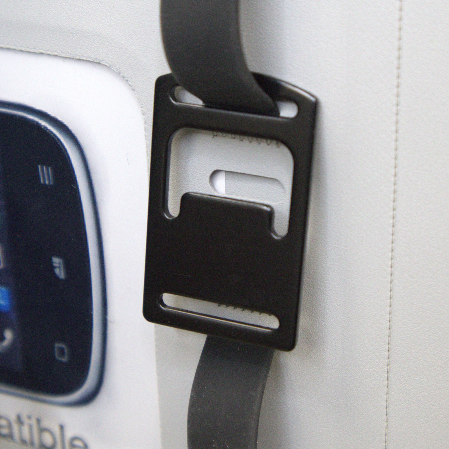 Car seat belt buckle attached to a car seat with a visible car console in the background.