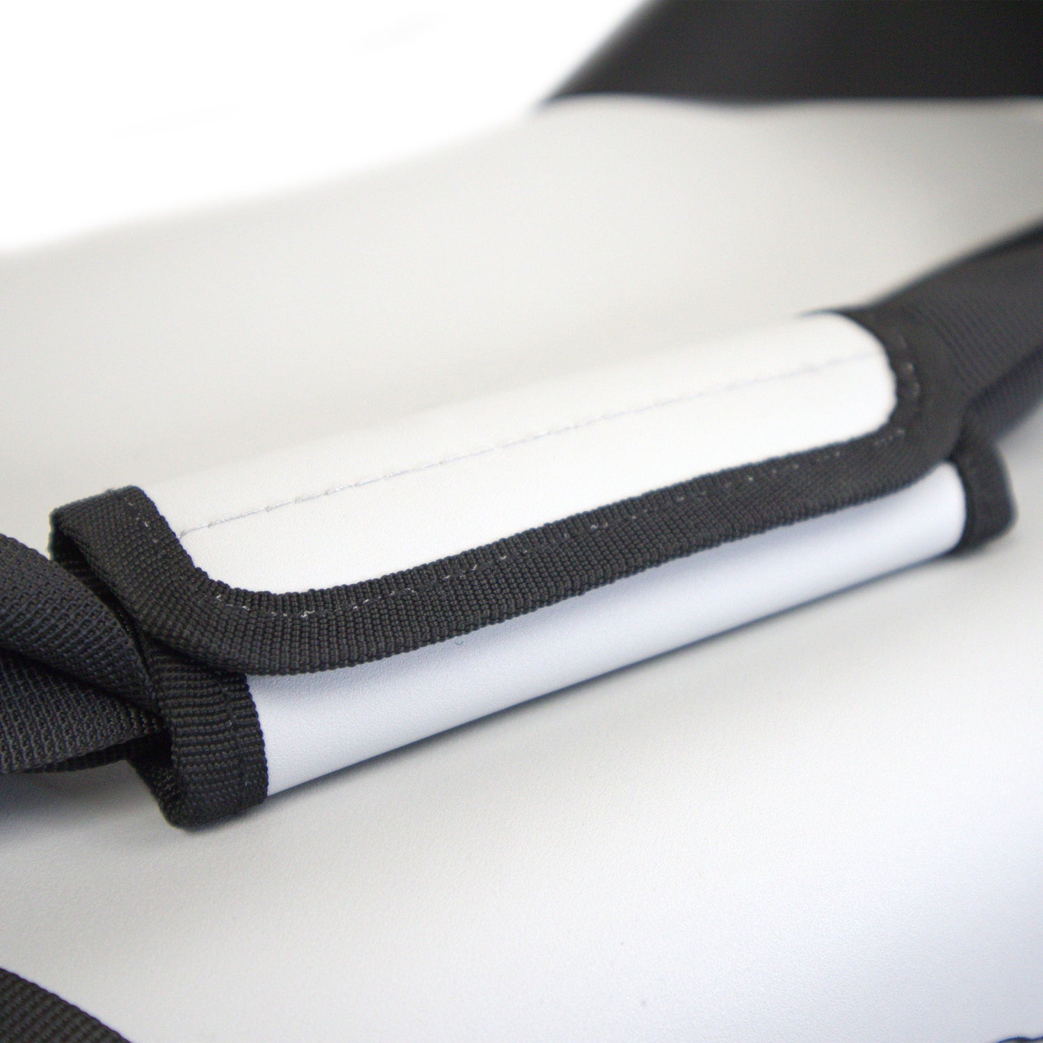 Close-up of a white and black protective gear with a strap on a light gray background