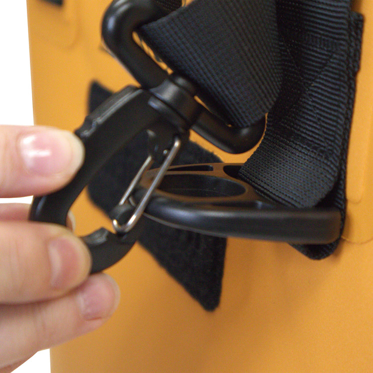 Close-up of a hand adjusting a black strap on an orange object.