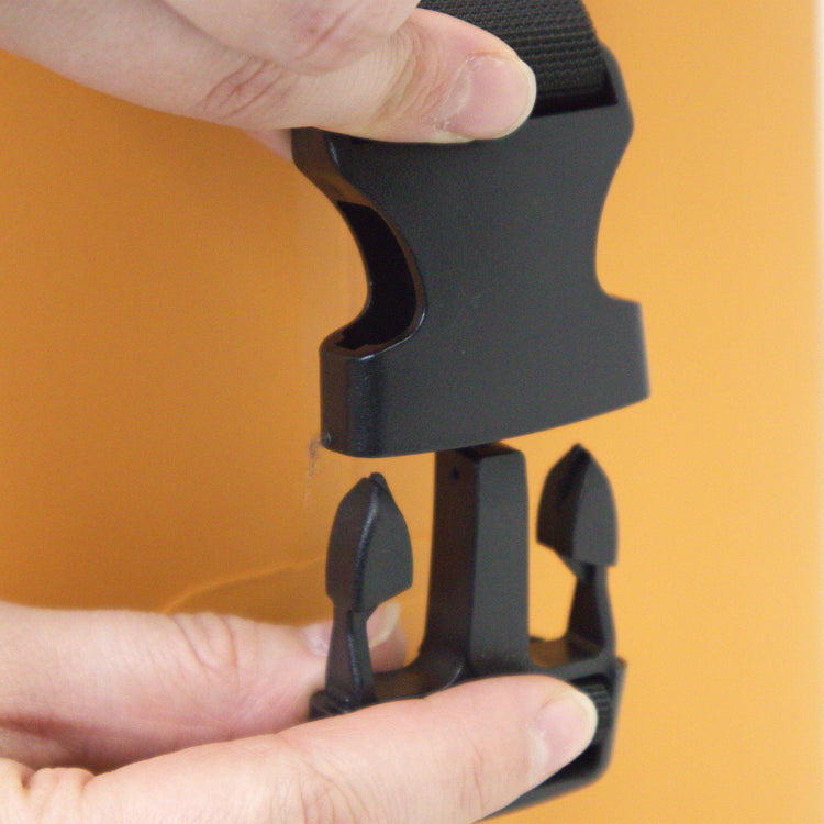 Black plastic tool held by a hand against an orange background