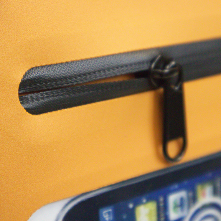 Close-up of a black zipper on an orange background