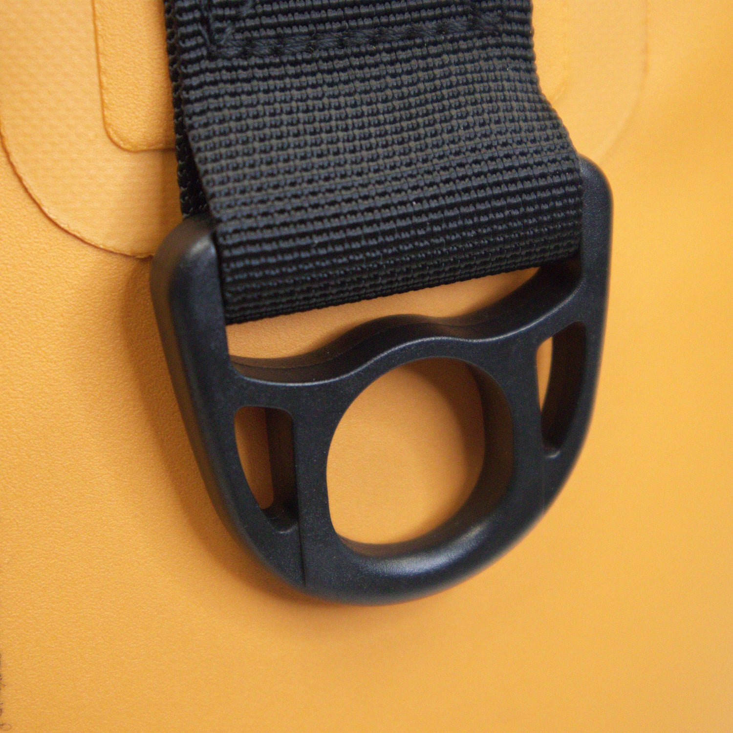 Close-up of a black strap with a buckle on a yellow background