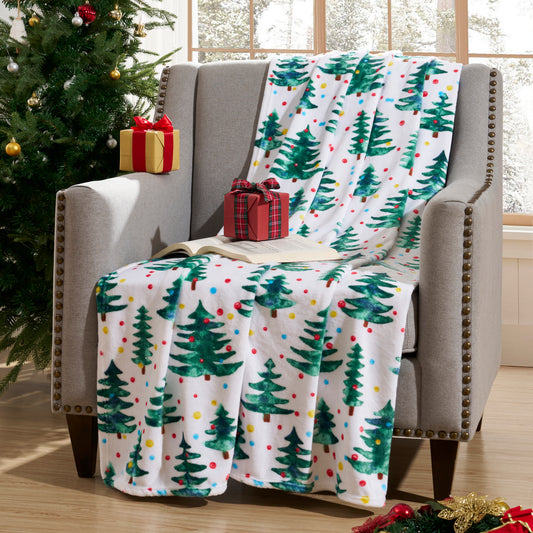 Christmas-themed blanket with trees and polka dots draped over a chair next to a decorated Christmas tree.