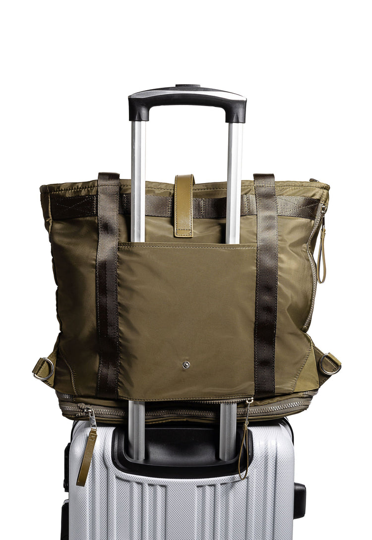 Green travel bag with black straps on top of a white suitcase