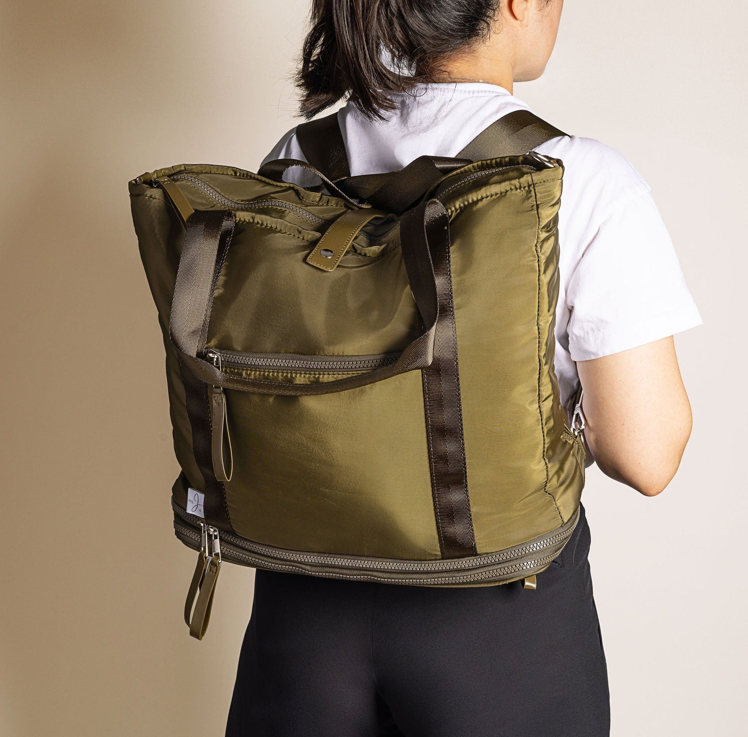 Person wearing a green backpack on a beige background