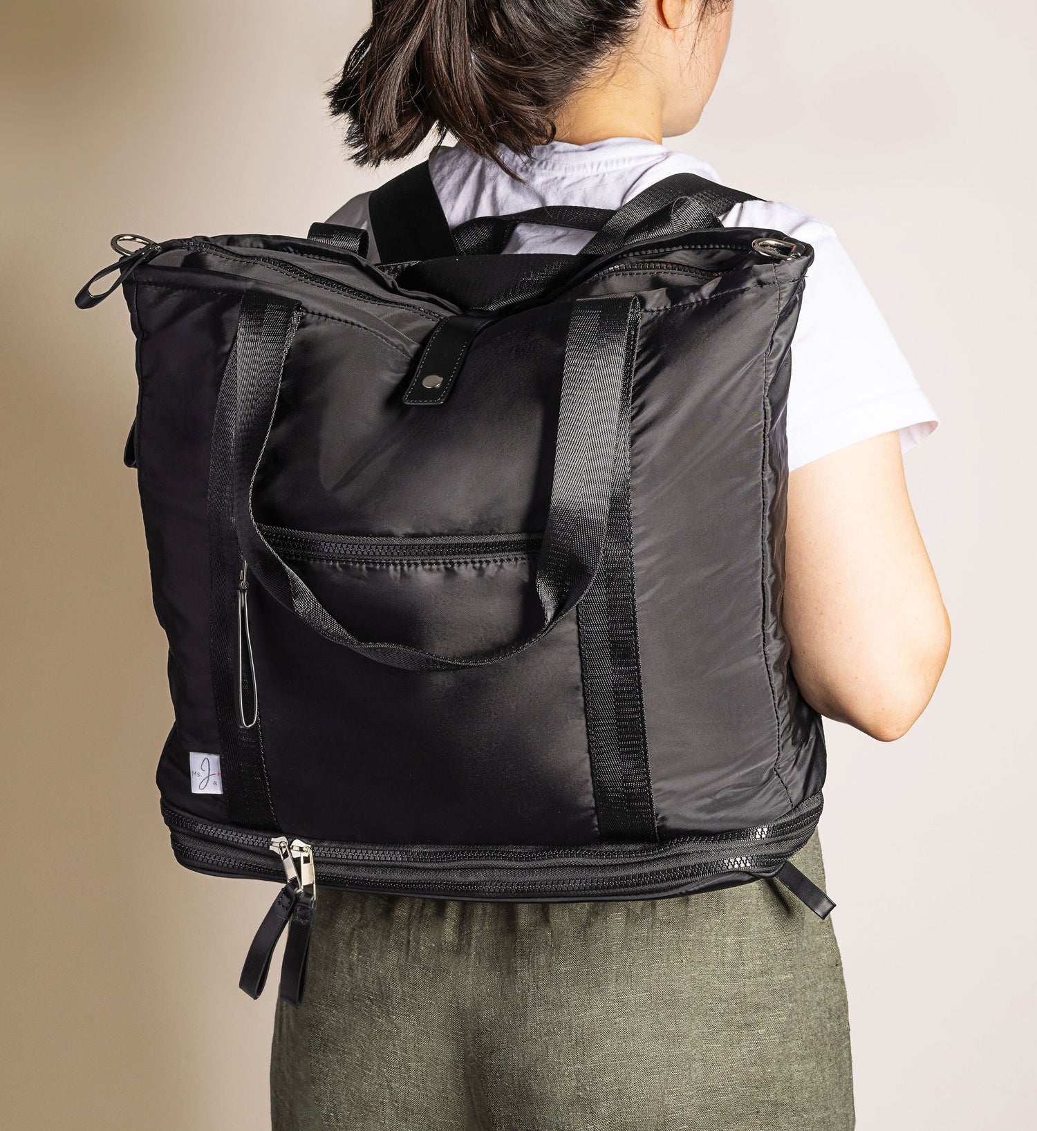 Person wearing a black backpack against a beige background