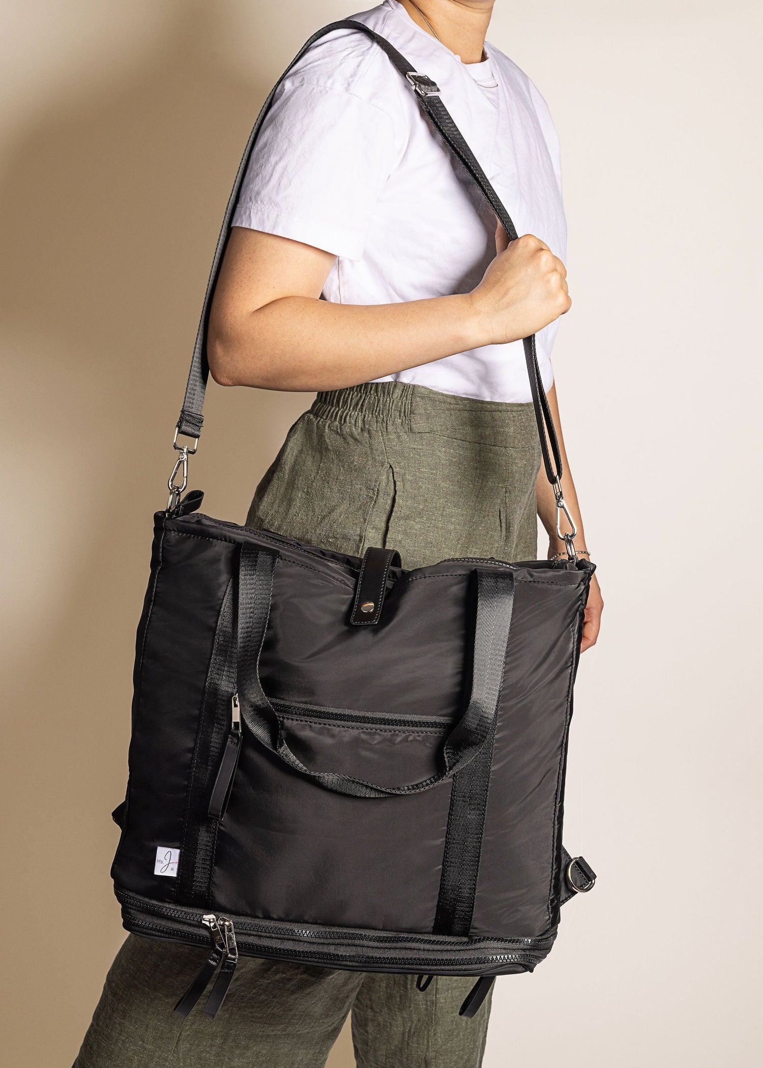 Person holding a black travel bag with a beige background
