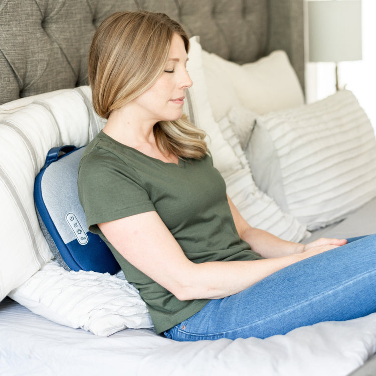 Woman using a back massager in a bedroom setting