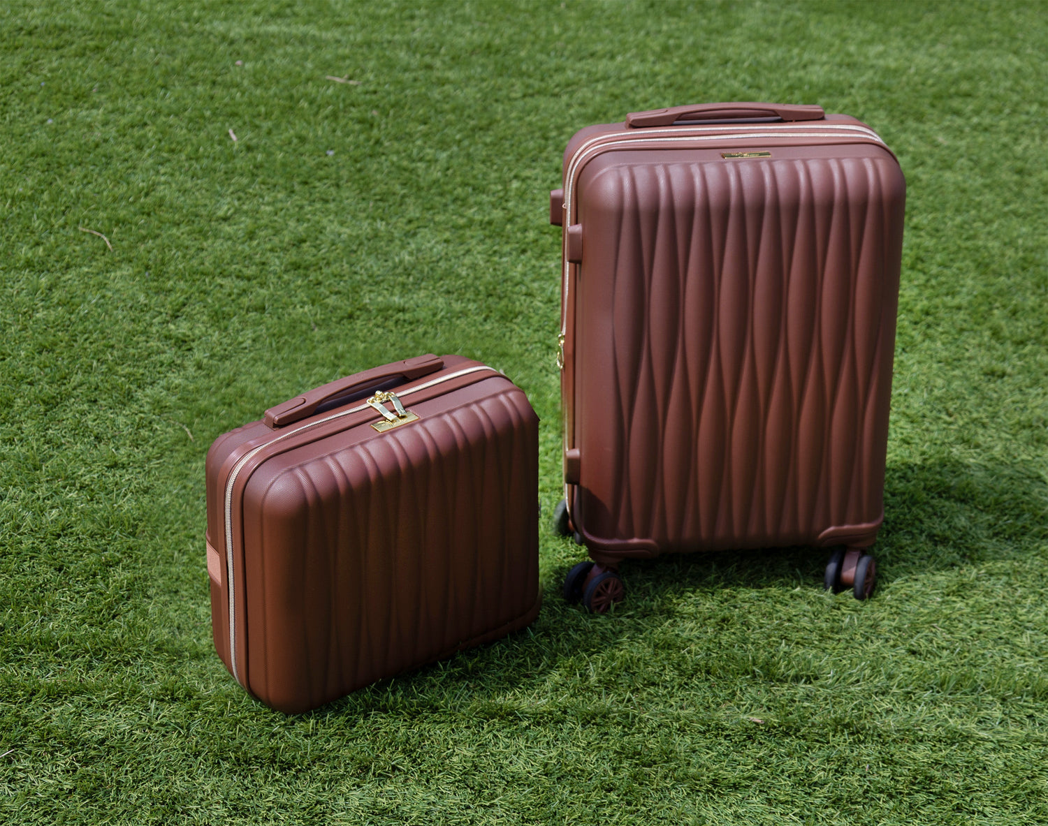 Two brown suitcases on a grassy surface