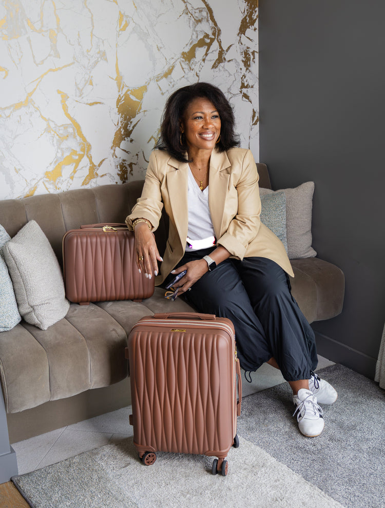 Woman sitting on a couch with two brown suitcases in a stylish room.