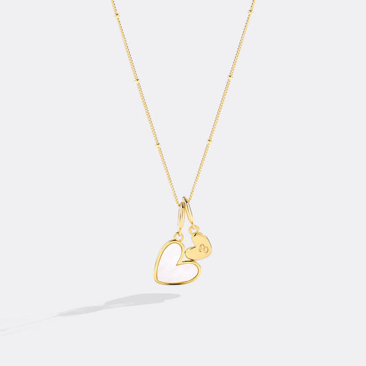 Gold necklace with a heart-shaped pendant on a white background