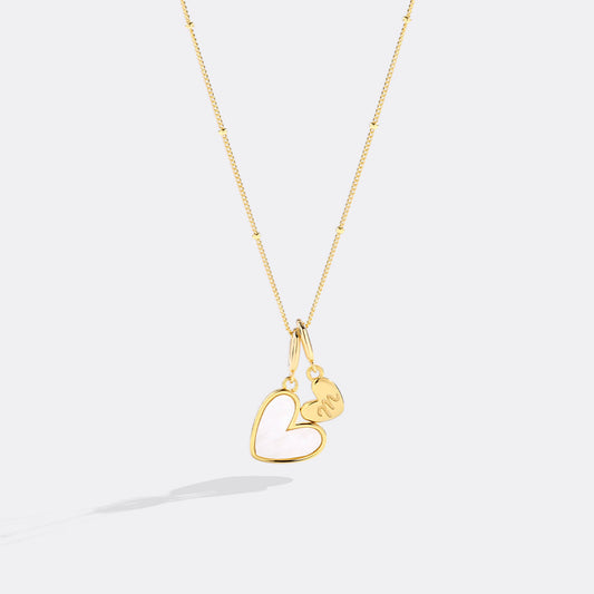 Gold necklace with a heart-shaped pendant on a white background