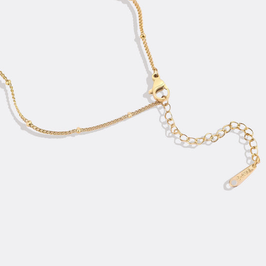 Gold necklace with a heart-shaped pendant on a white background
