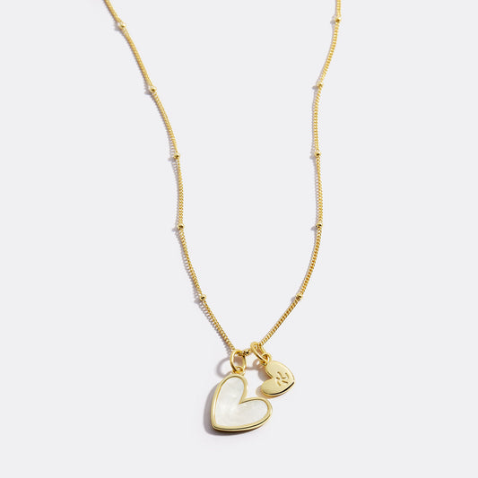 Gold necklace with a heart-shaped pendant on a white background