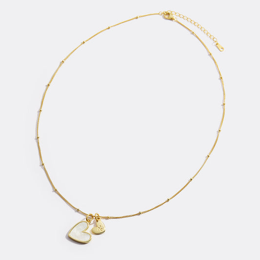 Gold necklace with a heart-shaped pendant on a white background