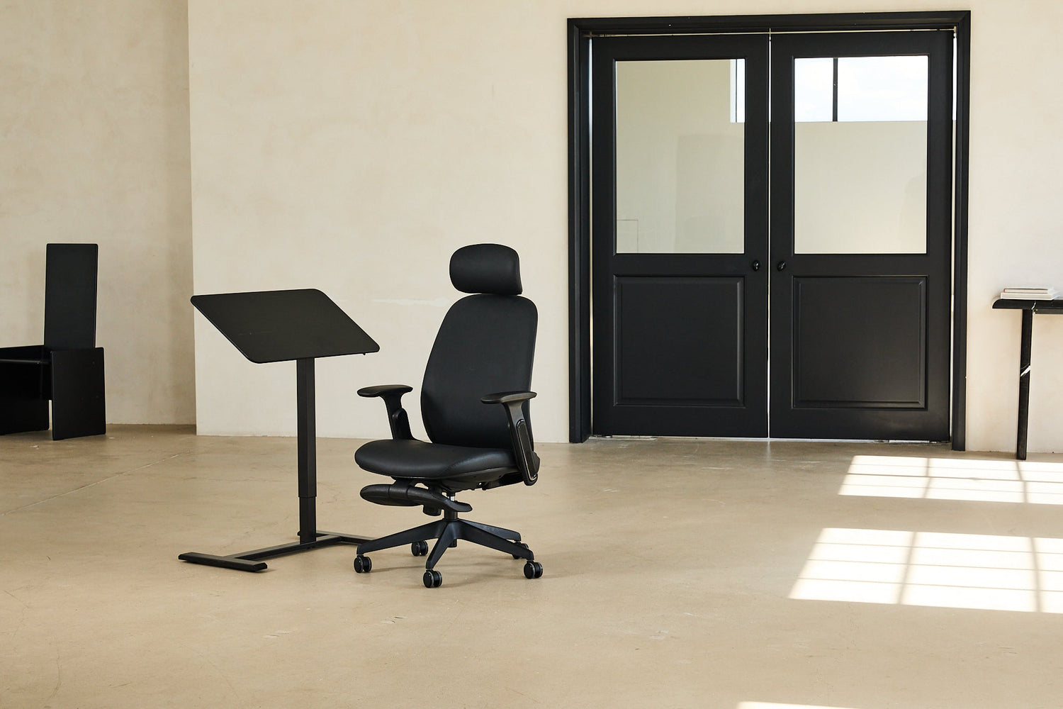 Black office chair in a room with a black door and tables.