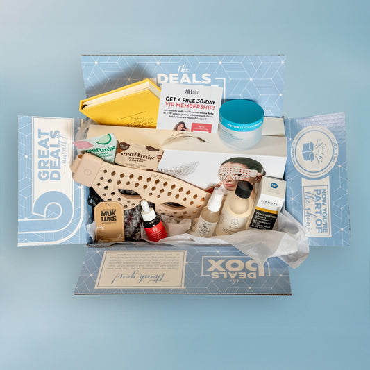 Open subscription box with various items including shoes, skincare products, and a face mask on a white background.