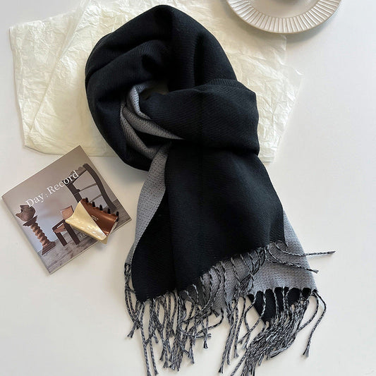 Black and gray scarf with fringes on a white surface next to a book.