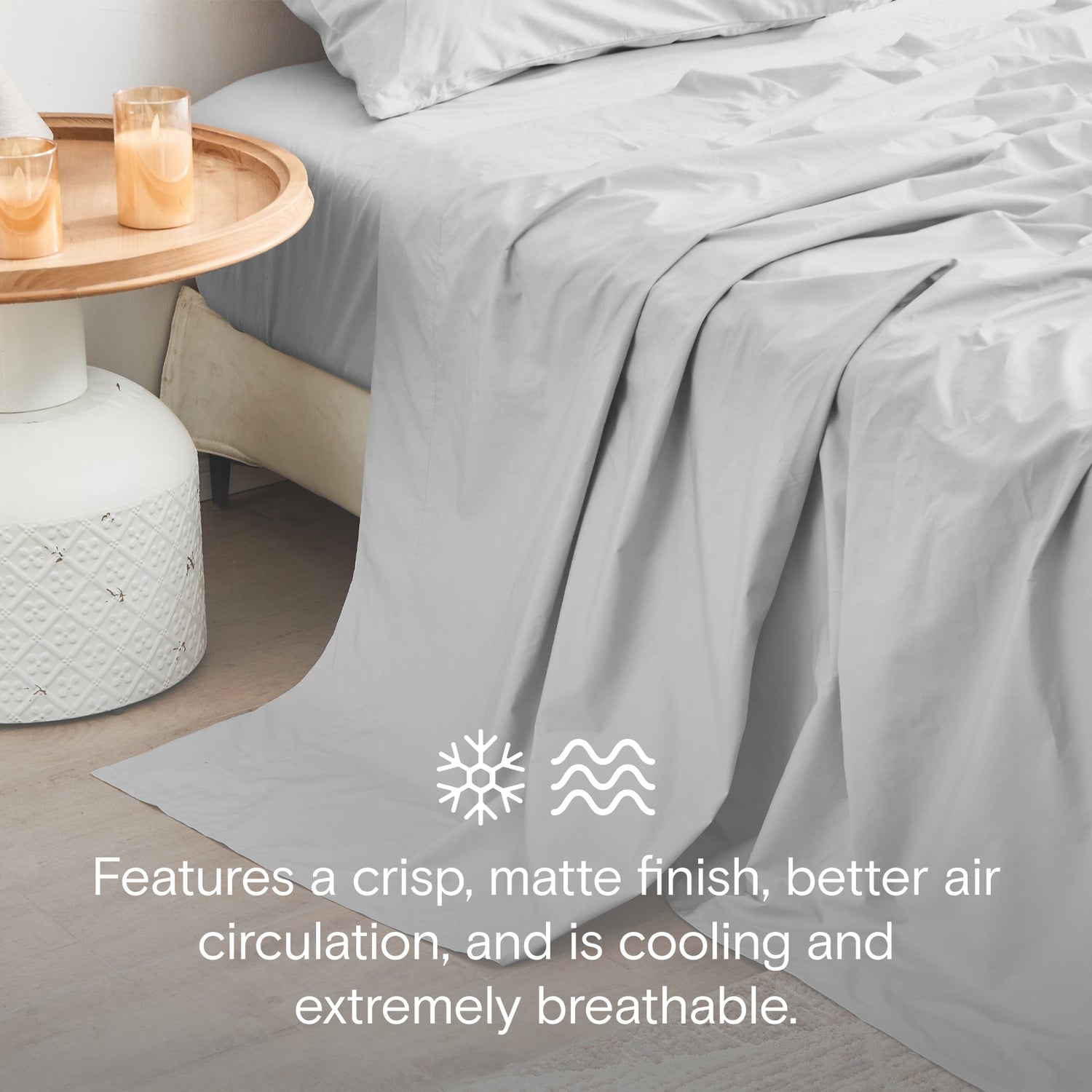 Gray bedding on a bed with a side table and candles, featuring text about bedding properties.