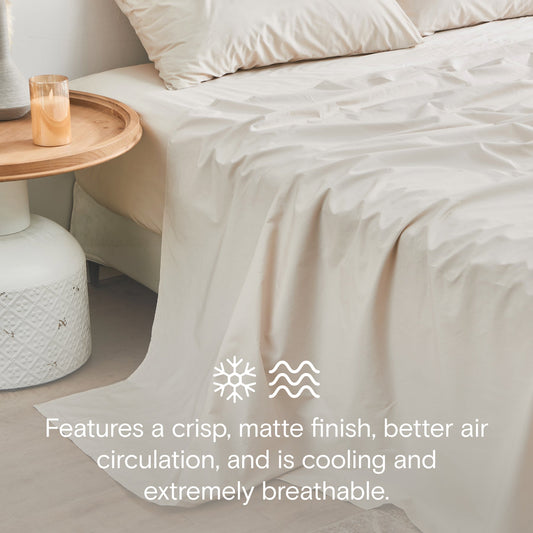 Neatly made bed with beige bedding in a bright bedroom.