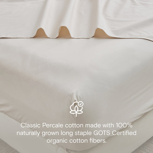 Neatly made bed with beige bedding in a bright bedroom.