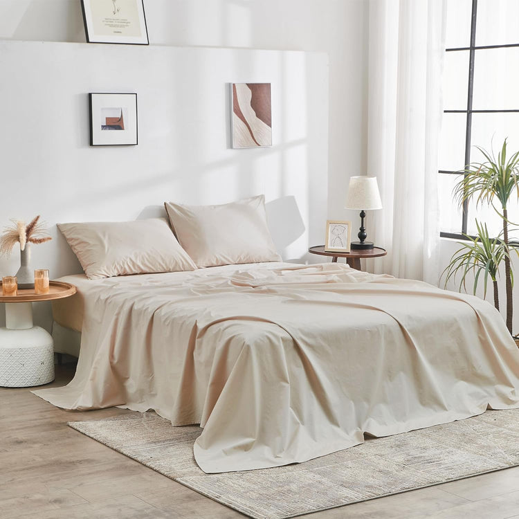 Neatly made bed with beige bedding in a bright bedroom.
