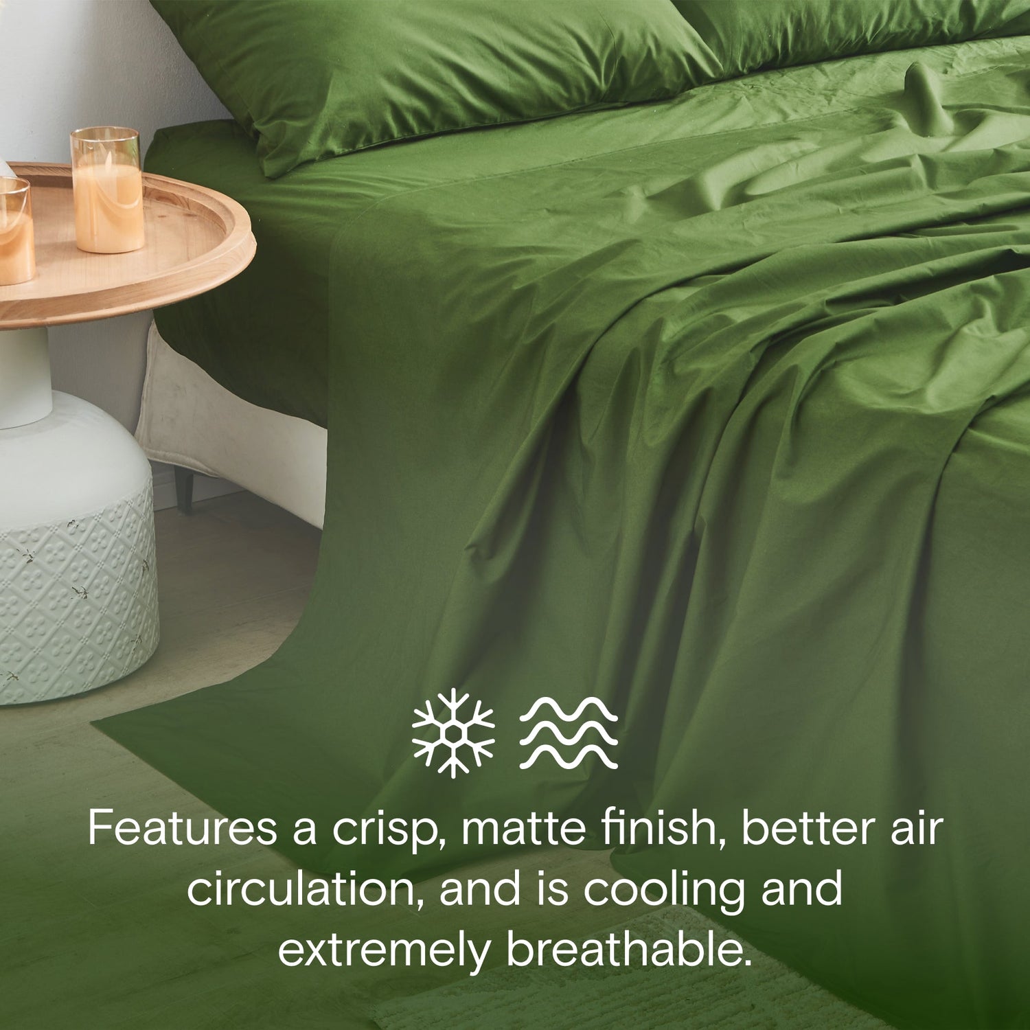 Green bed sheets on a bed with a side table and candles in the background.