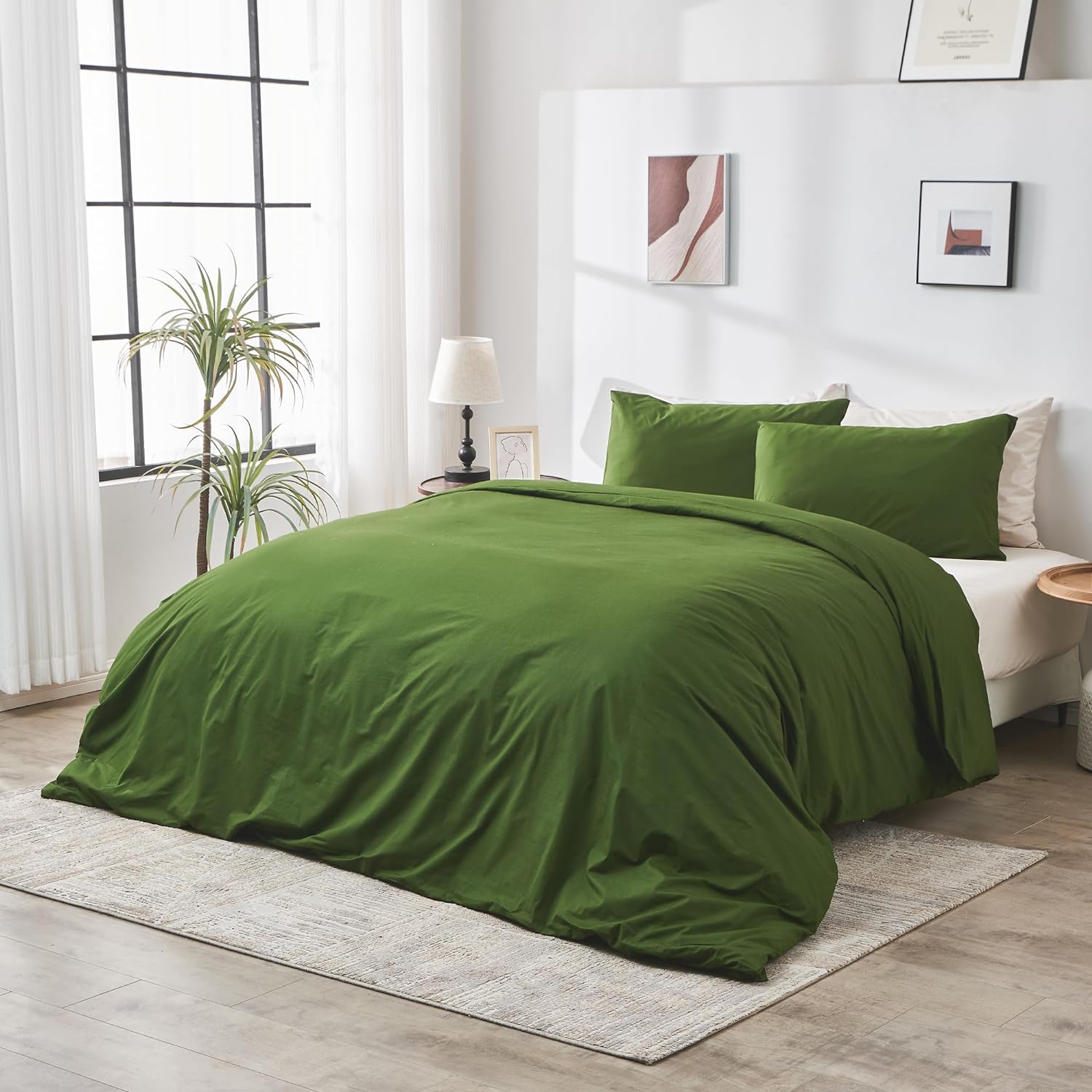 Green bedspread on a bed in a bright bedroom with large windows and decor.