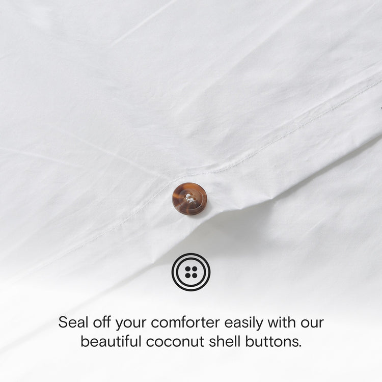 Close-up of a white comforter with a coconut shell button and text about using buttons.