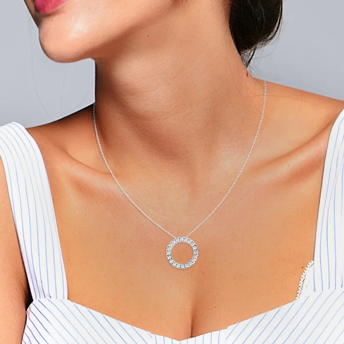 Silver necklace with a circular pendant worn by a person