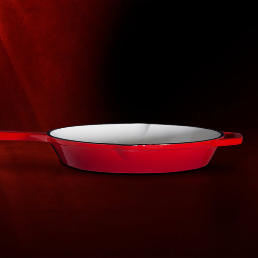 Red enameled cast iron skillet on a white background