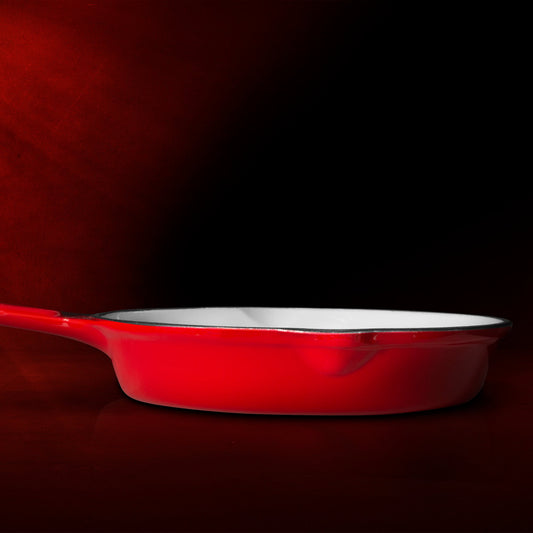 Red frying pan with a white interior on a white background