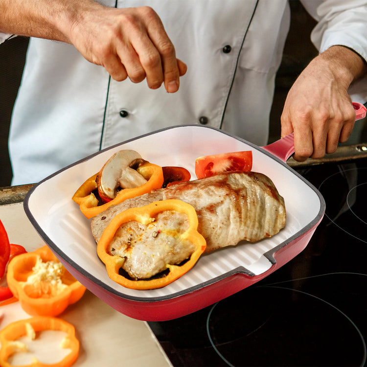 Person cooking with a red and white grill pan on a stovetop