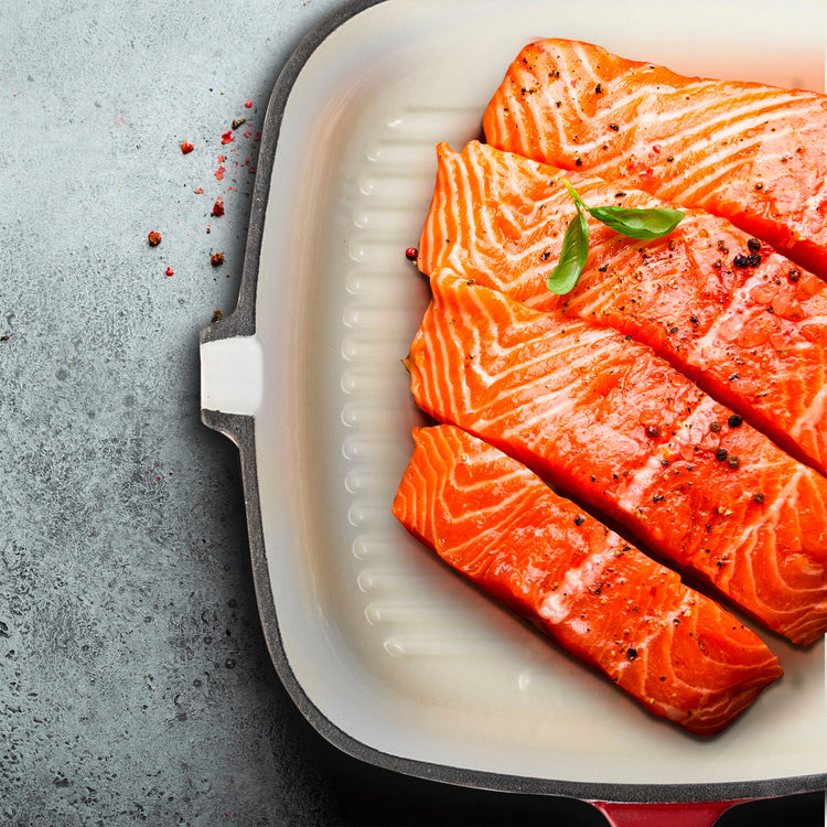 Raw salmon fillets in a white dish on a gray surface
