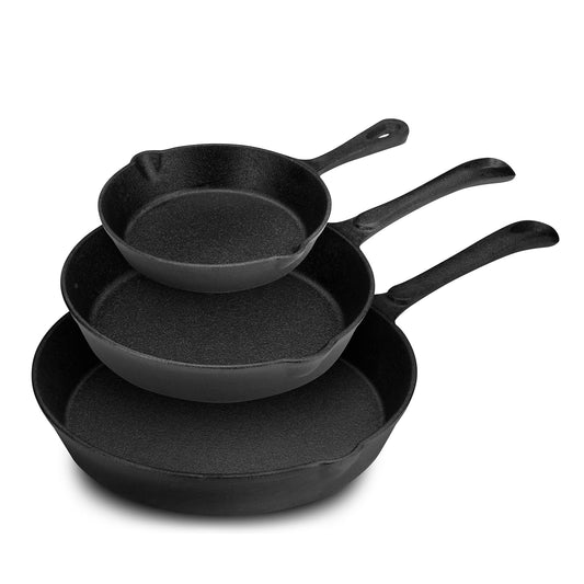Set of three black cast iron skillets on a white background