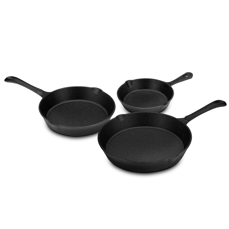 Set of three black cast iron skillets on a white background