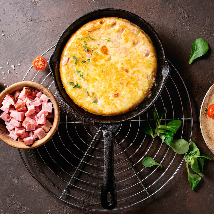 Skillet with frittata on a dark surface with ingredients around