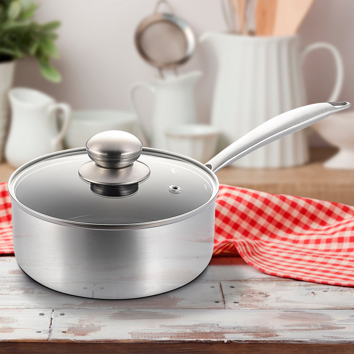 Silver saucepan with lid on a wooden surface with a red and white checkered cloth