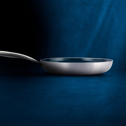 Stainless steel frying pan with a blue non-stick coating on a white background