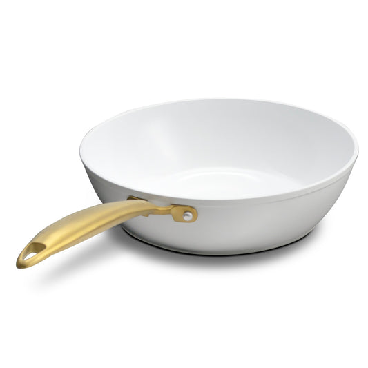 White frying pan with a gold handle on a white background