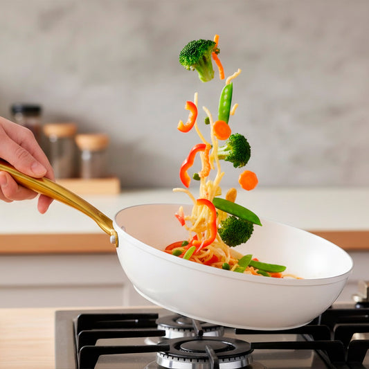 White frying pan with a gold handle on a white background