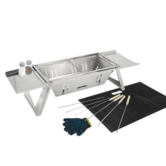 A stainless steel outdoor grill set with side tables, shown with salt and pepper shakers, a black grill mat, a blue heat-resistant glove, and several long skewers on a white background.