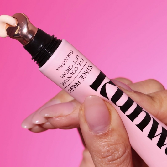 Pink lip balm tube with black text held against a pink background