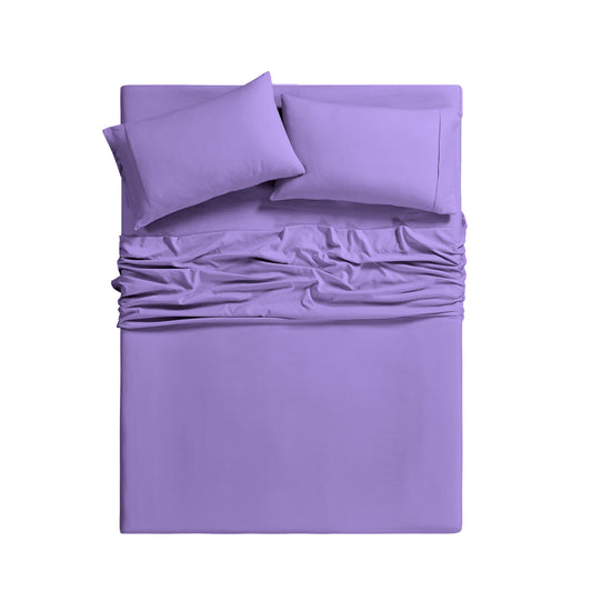 Purple bedding set on a bed in a room with large windows.